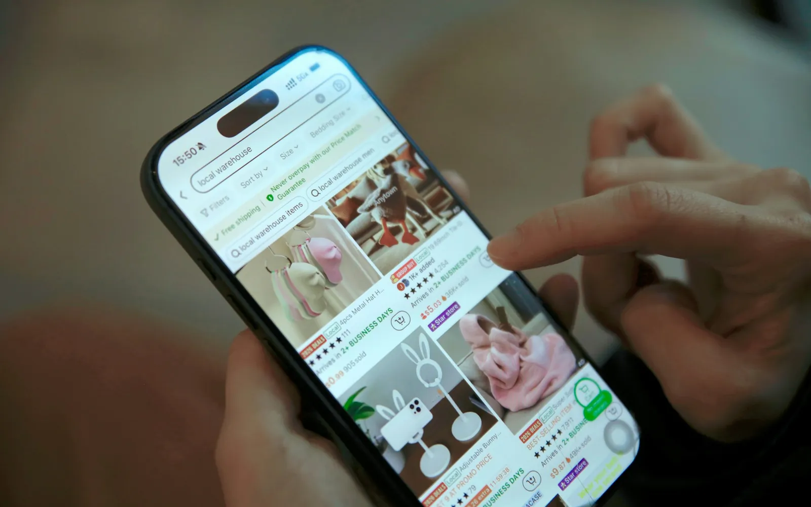 A hand scrolling a grid of products in a shopping app on a smartphone
